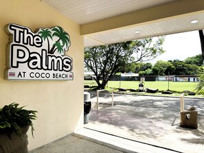 Une enseigne pour « The Palms at Coco Beach », avec un logo représentant un palmier.
