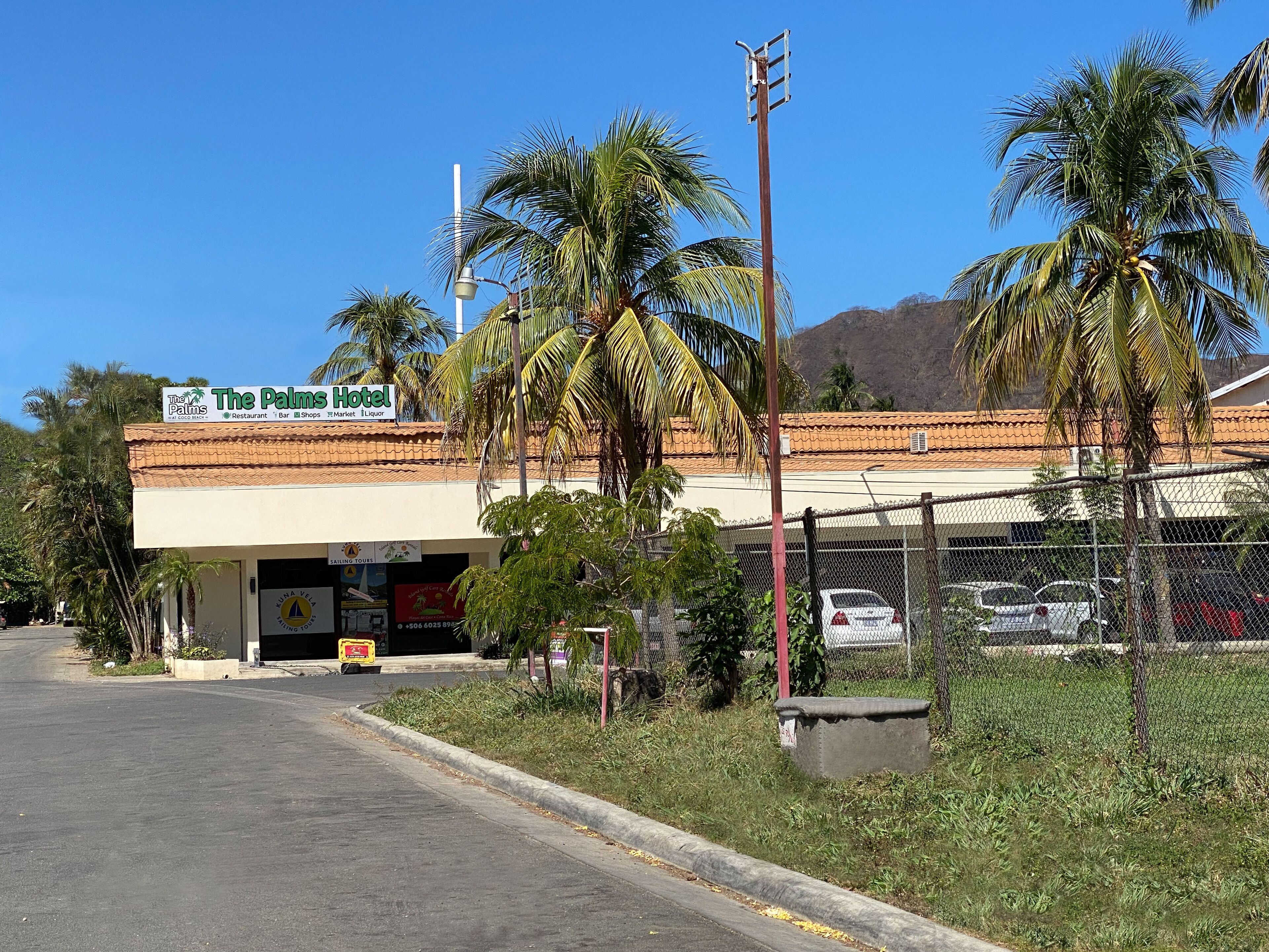 The Palms Hotel with a signboard, a parking lot, and palm trees.