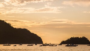 A coastal scene with boats on calm waters, surrounded by cliffs and small islands.