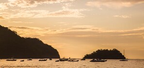 A coastal scene with boats on calm waters, surrounded by cliffs and small islands.