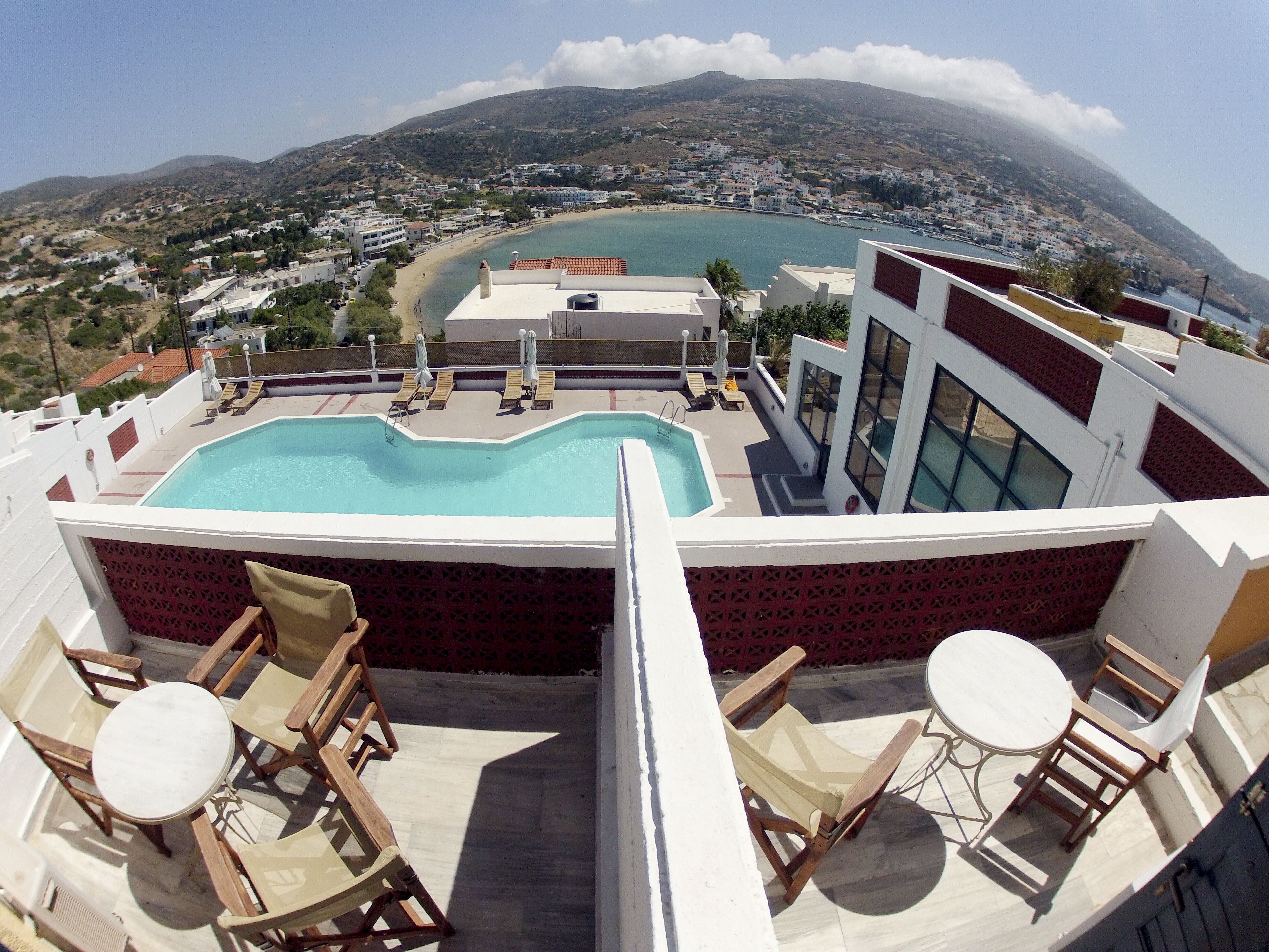 A rooftop pool with lounge chairs and a view of a coastal town.