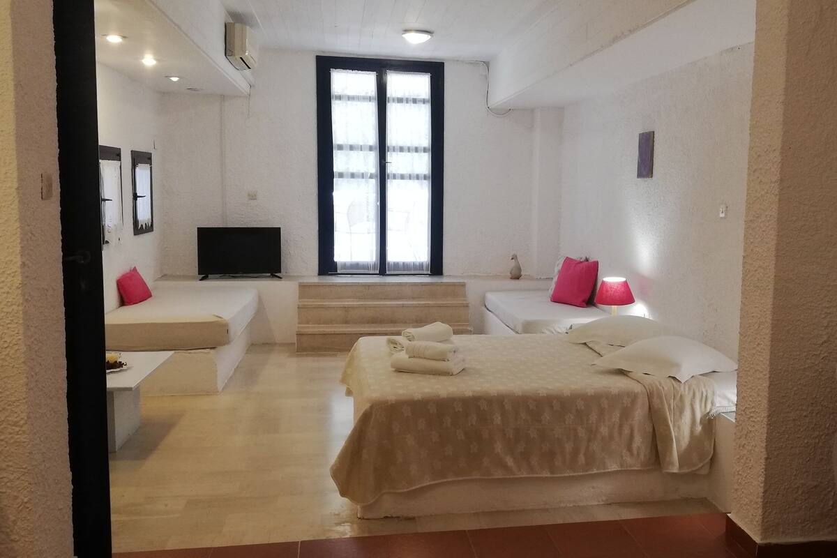 Een hotelkamer met een bed, een bank, een televisie en een trap naar het balkon.