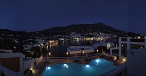 A nighttime view of a resort with a pool, overlooking a body of water and a cityscape. - Mare Vista Hotel - Epaminondas (Andros)