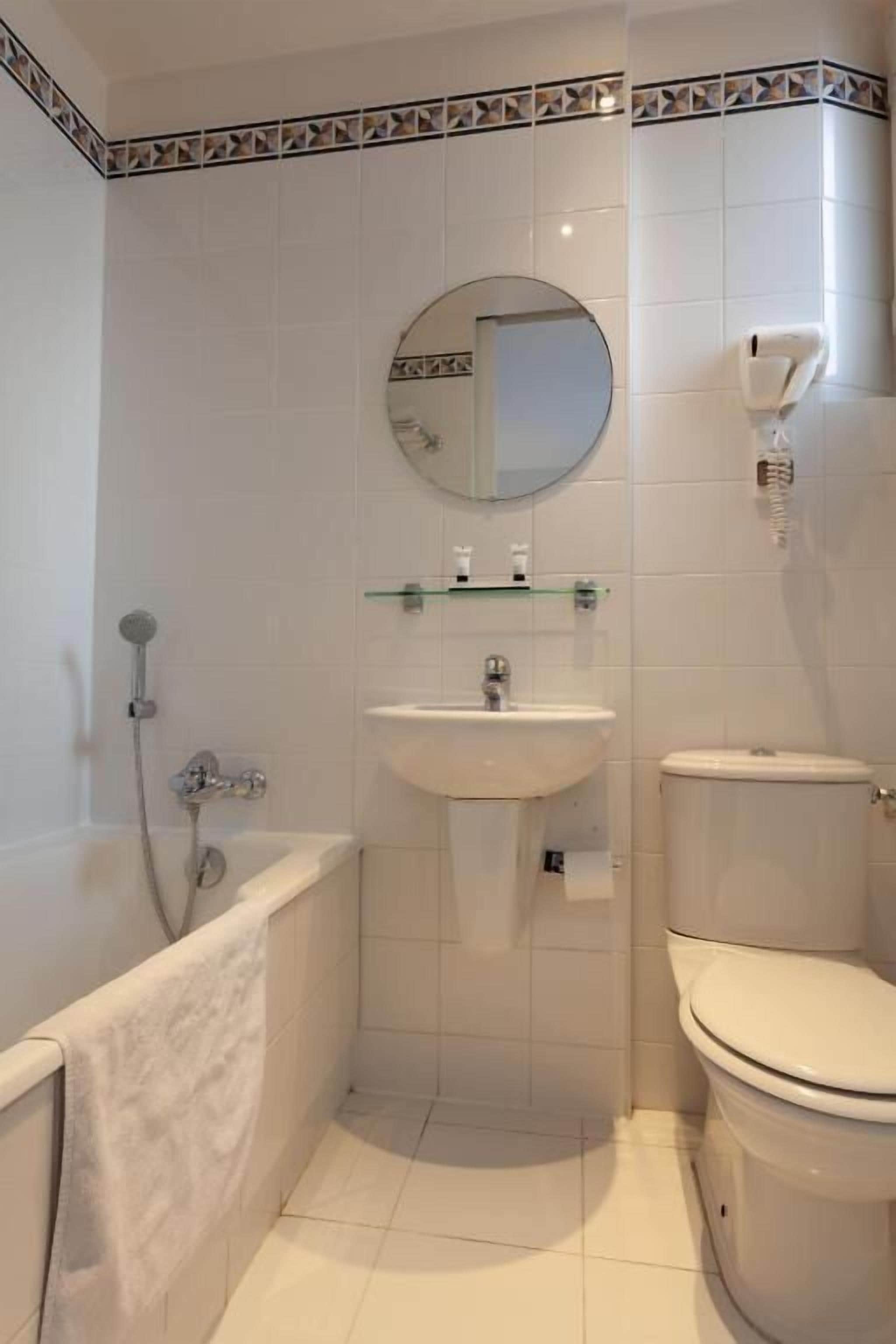 Un baño pequeño con bañera, lavabo, inodoro y espejo.