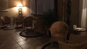 Una habitación tenuemente iluminada con muebles de mimbre, una pequeña mesa y una lámpara.