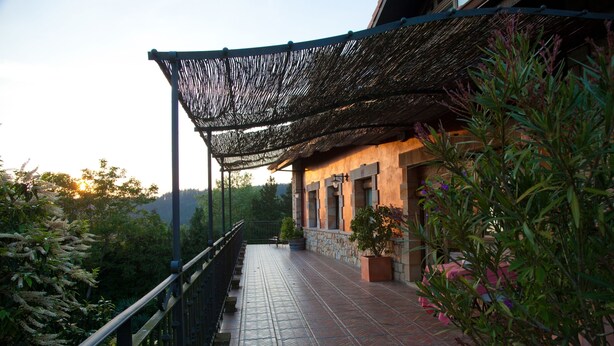 Un balcón con piso estampado, una pérgola y plantas en macetas.