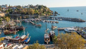 Un pueblo costero con un puerto deportivo lleno de barcos, un fuerte histórico y vistas al mar.