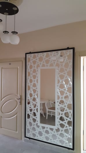 A room with a beige door, a decorative white partition with geometric patterns, and a ceiling light fixture.