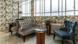 A room with a grey sofa, a blue armchair, and a round table with a marble top. - Hotel Corvinus (Vienna)