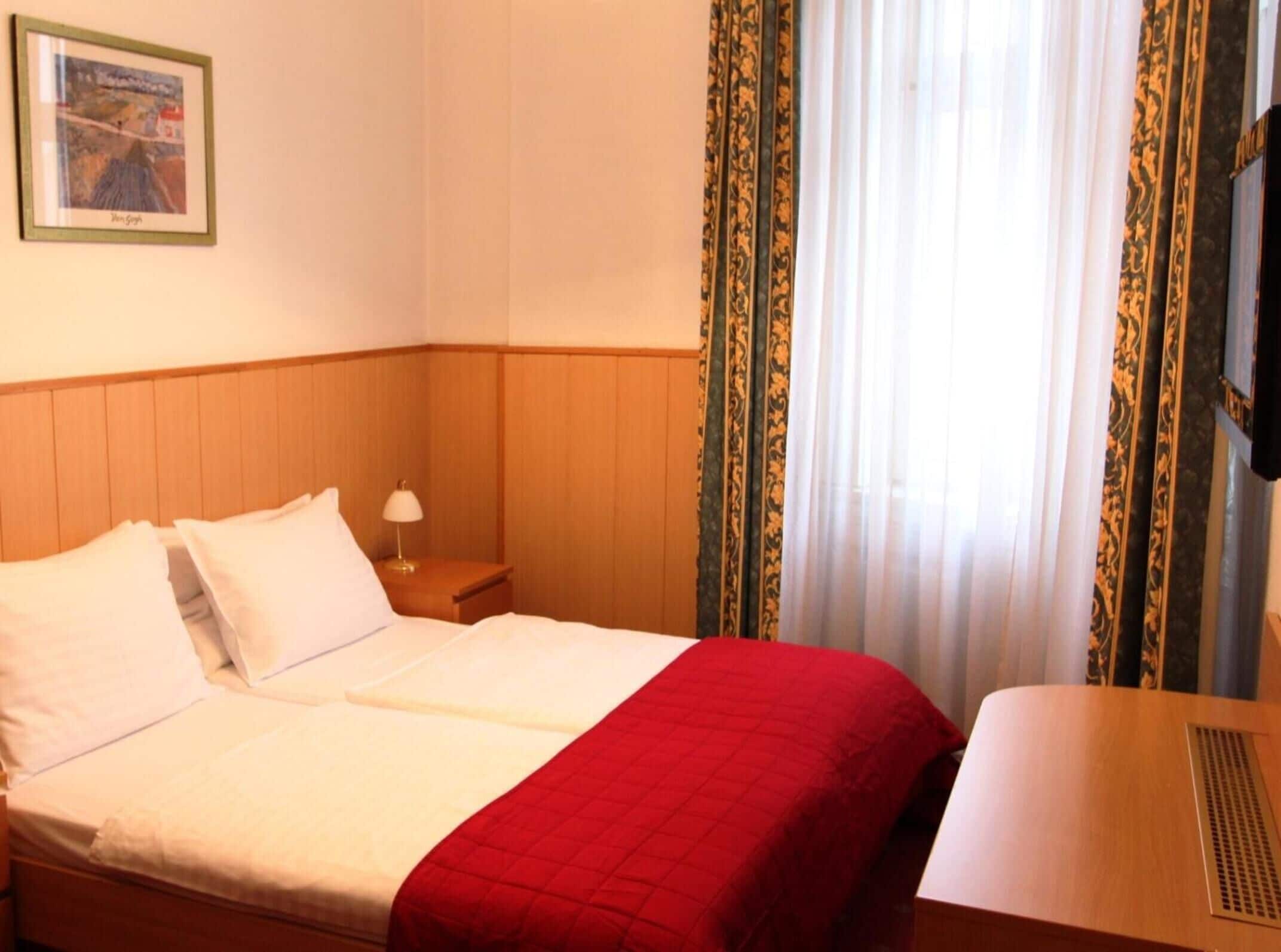 Une chambre d’hôtel avec un lit, une table de chevet, une lampe et un tableau au mur.