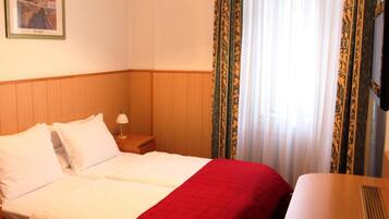 Une chambre d’hôtel avec un lit, une table de chevet, une lampe et un tableau au mur.