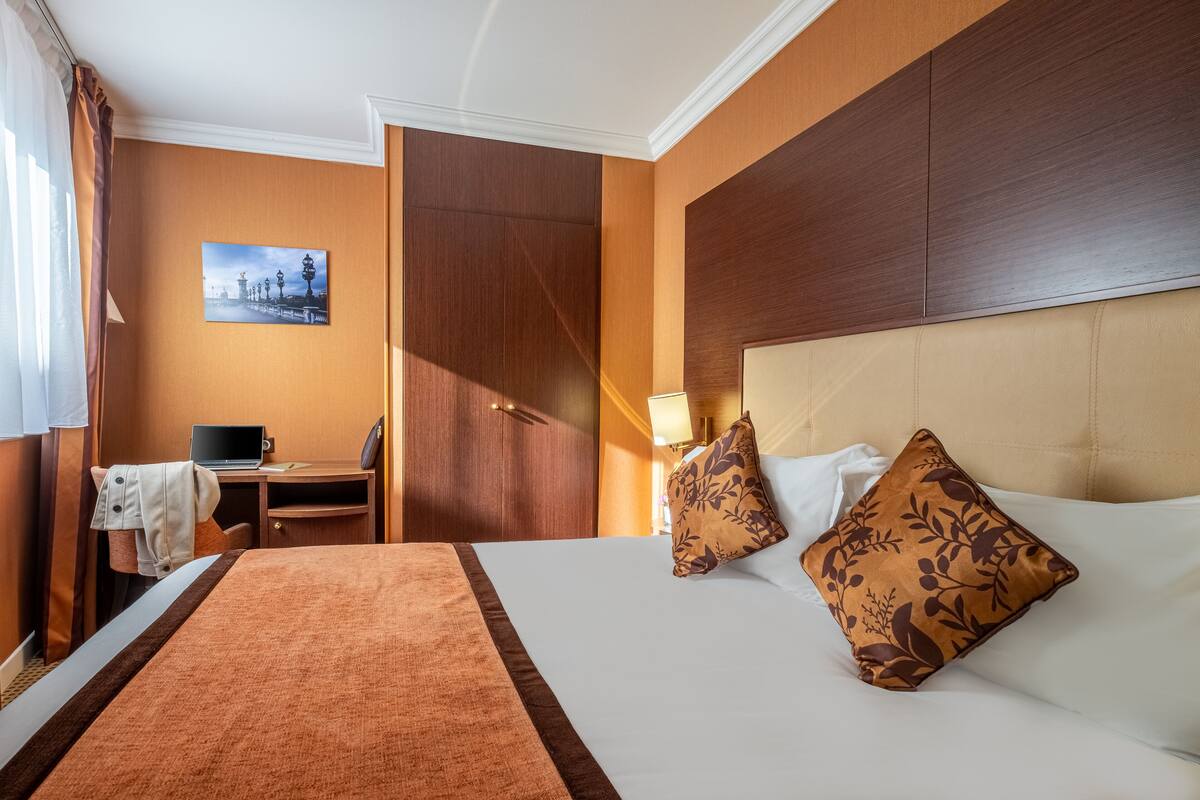 A hotel room with a bed, a desk, and a chair.