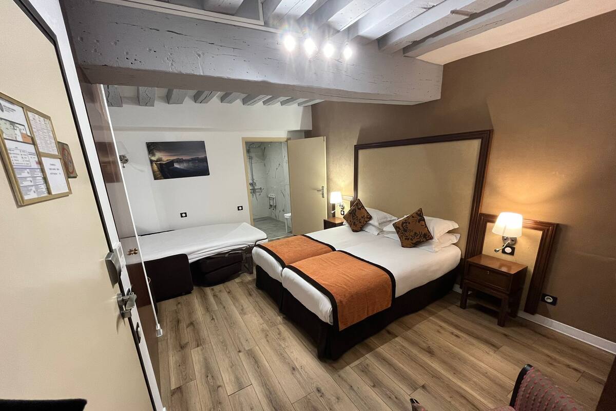 A hotel room with a bed, a desk, and a chair.