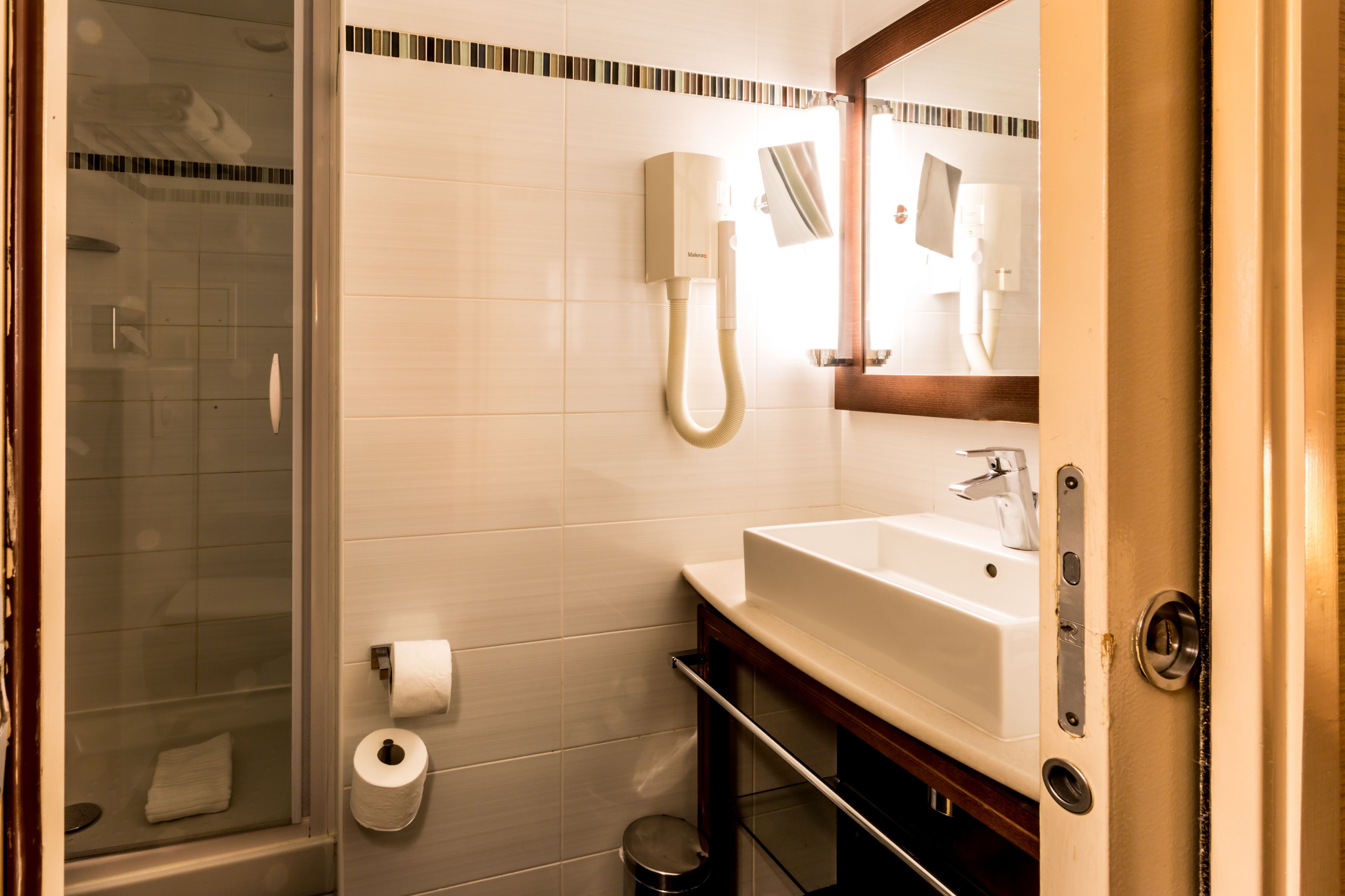 A bathroom with a glass shower enclosure, a white sink, a toilet, and a towel rack.