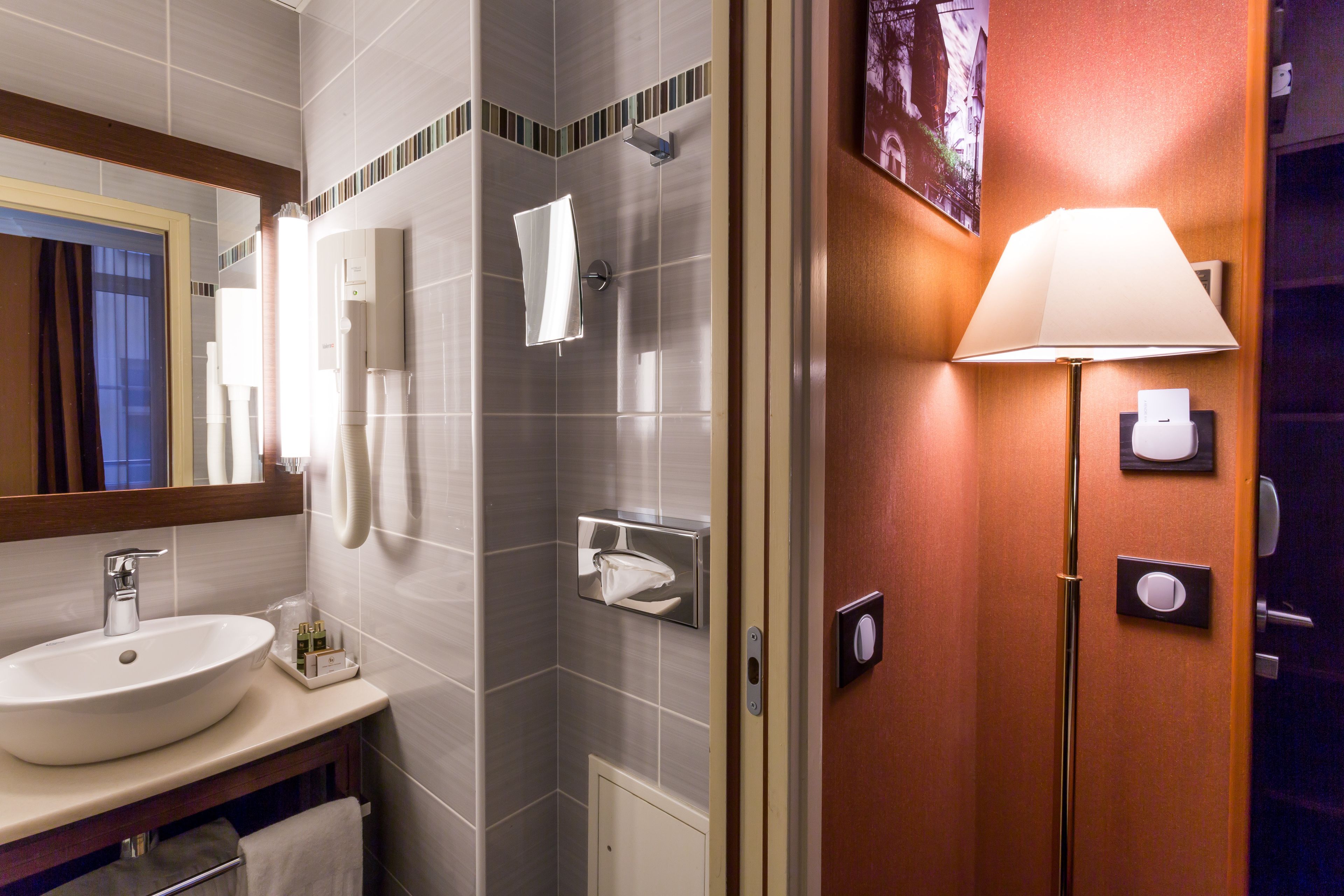 Une salle de bain moderne équipée d’un lavabo, d’un miroir, d’un porte-serviettes et d’un espace douche.