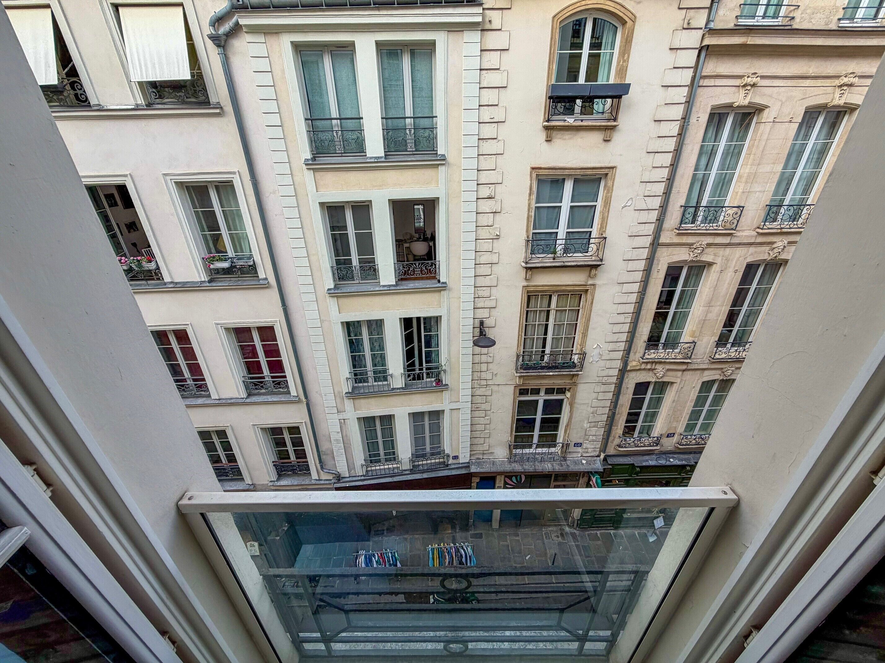 A view of a multi-story building with balconies, large windows, and a glass railing.