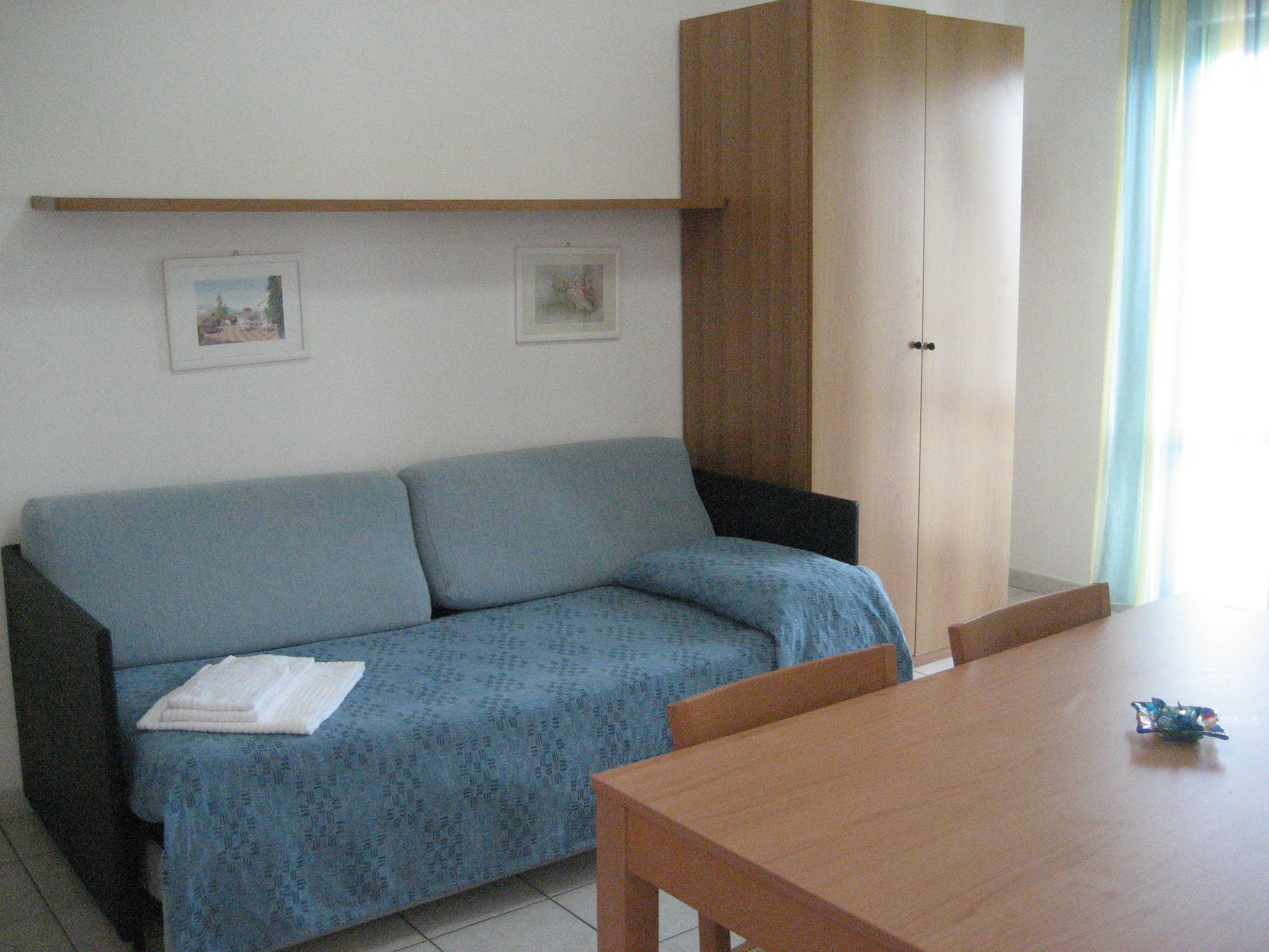 A room with a blue sofa, a wooden table, and a cabinet.