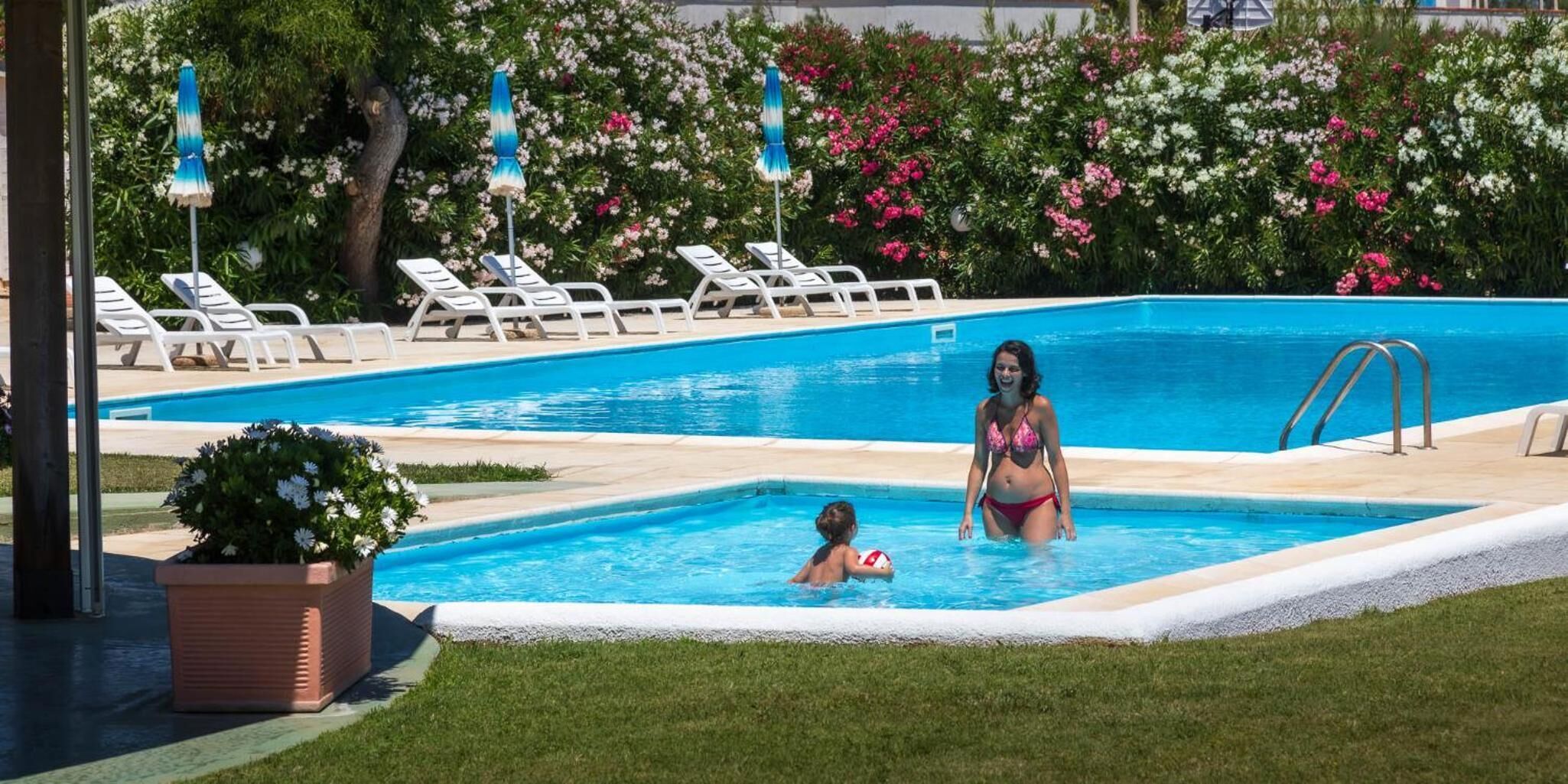 A swimming pool with lounge chairs and a small child playing.