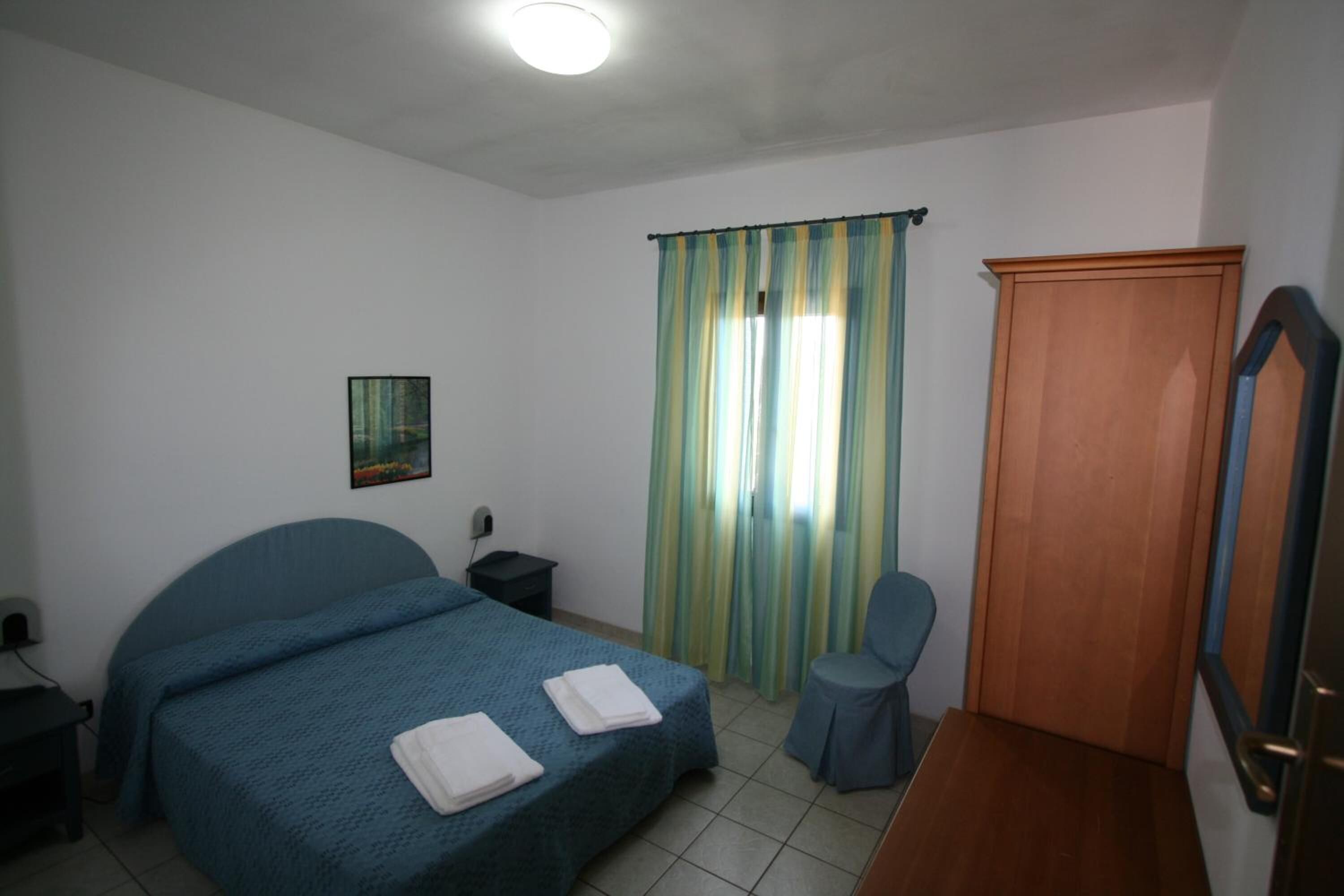 Ein Schlafzimmer mit zwei Betten, einem Sessel, einem Holzschrank und einem Bild an der Wand.