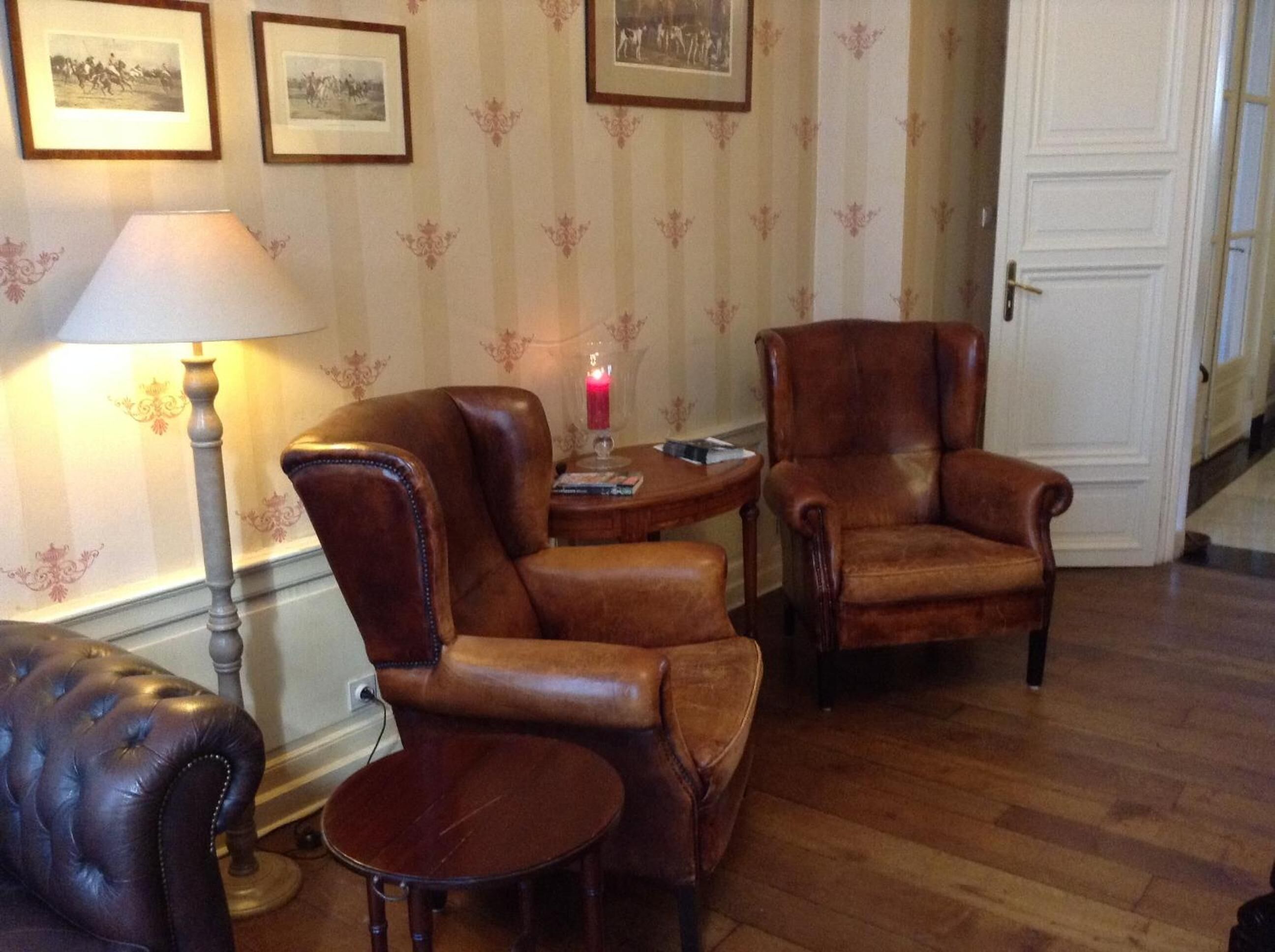 A room with two leather armchairs, a small round table, and a lamp.