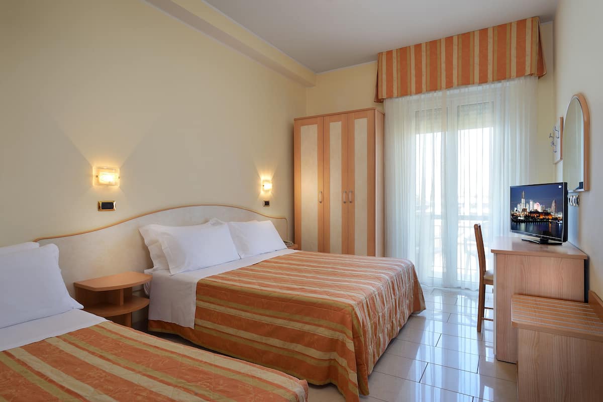 Une chambre d’hôtel avec deux lits, un bureau, une chaise, une télévision et une armoire.