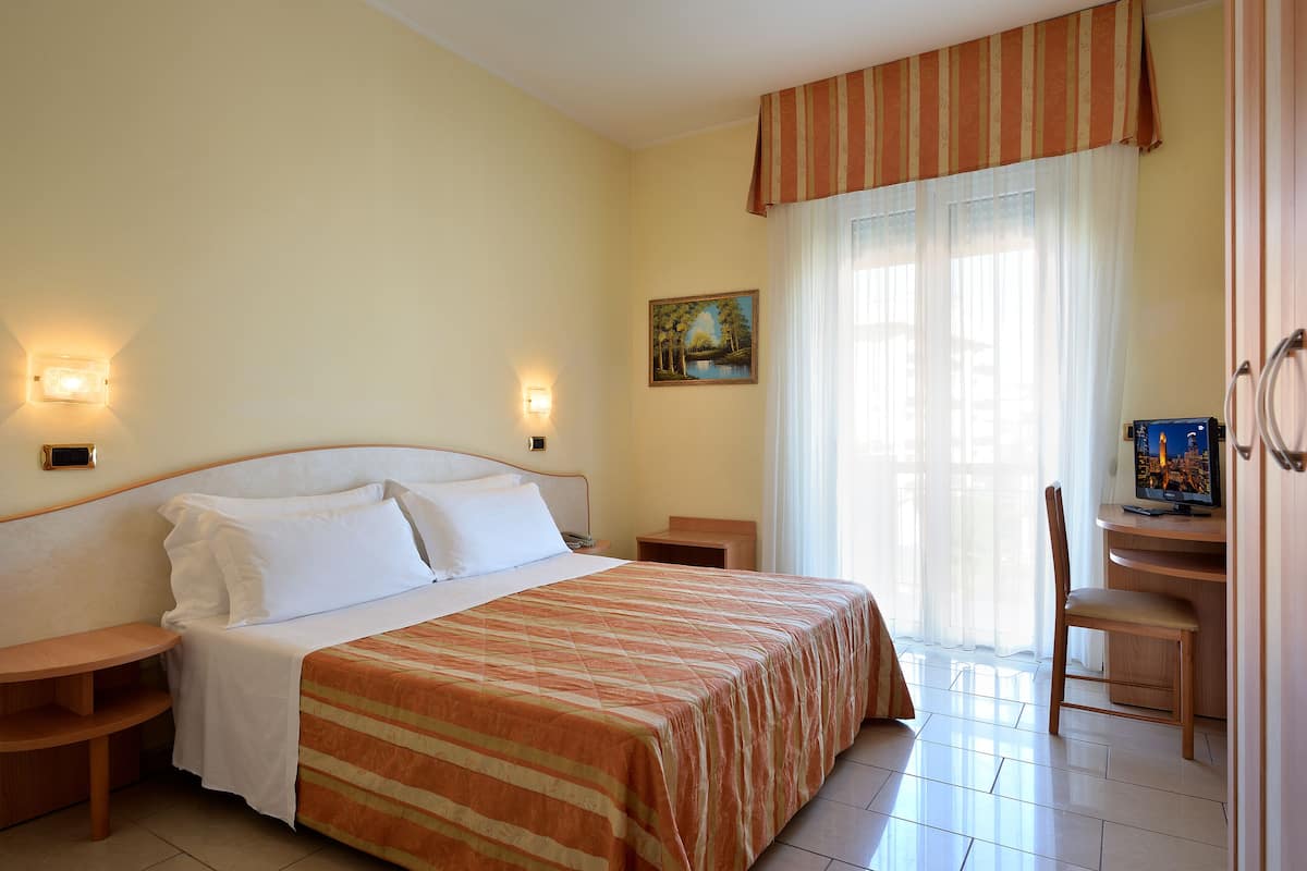 Une chambre d’hôtel avec un lit, des tables de chevet, un bureau et une chaise.
