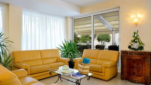 Una sala de estar con dos sofás amarillos, una mesa de centro de vidrio, una planta en maceta y un mueble de madera.
