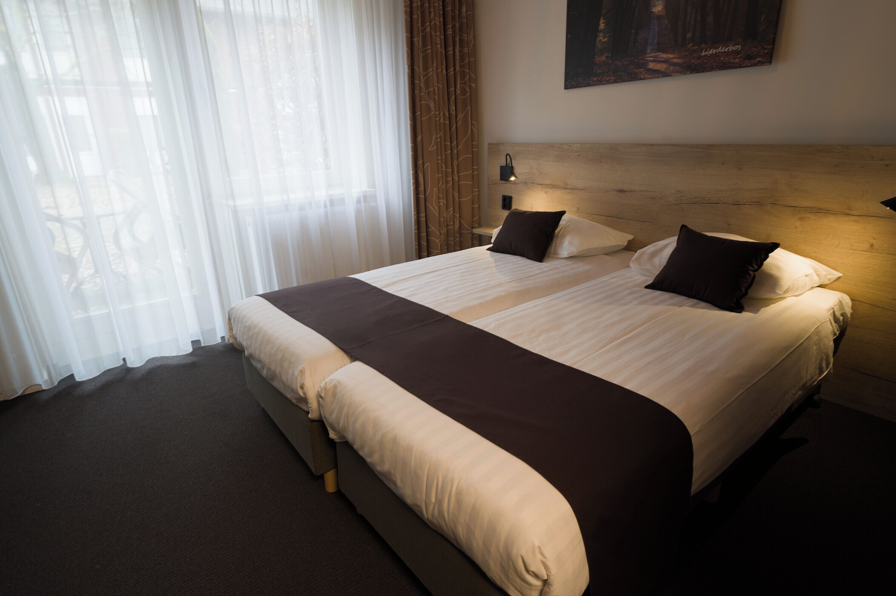 A double bed with a wooden headboard, two bedside tables, and a nightstand with a lamp.