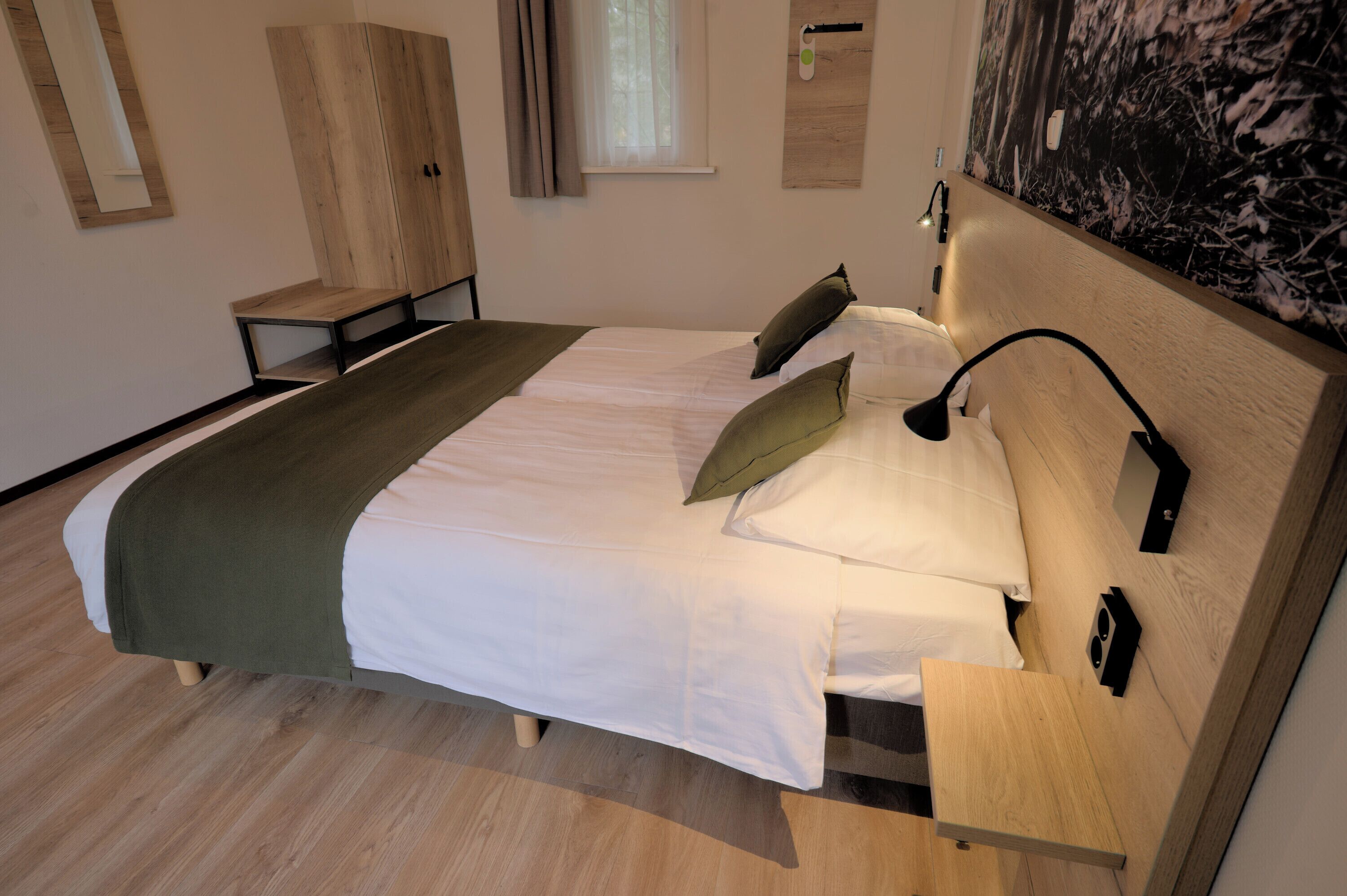 A neatly arranged bedroom with a bed, bedside tables, a wardrobe, and a wall-mounted artwork.