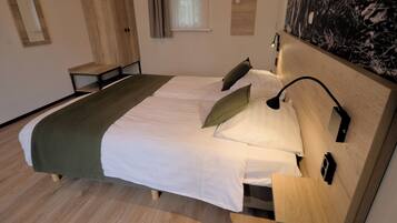 A neatly arranged bedroom with a bed, bedside tables, a wardrobe, and a wall-mounted artwork.