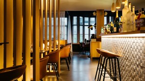 Zona de bar moderna con una barra larga, taburetes y una variedad de botellas.