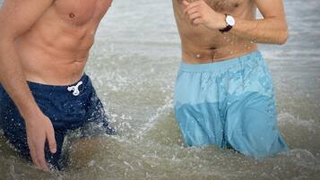 Two men in the water, one wearing blue shorts and the other in dark shorts, with a watch on his wrist.