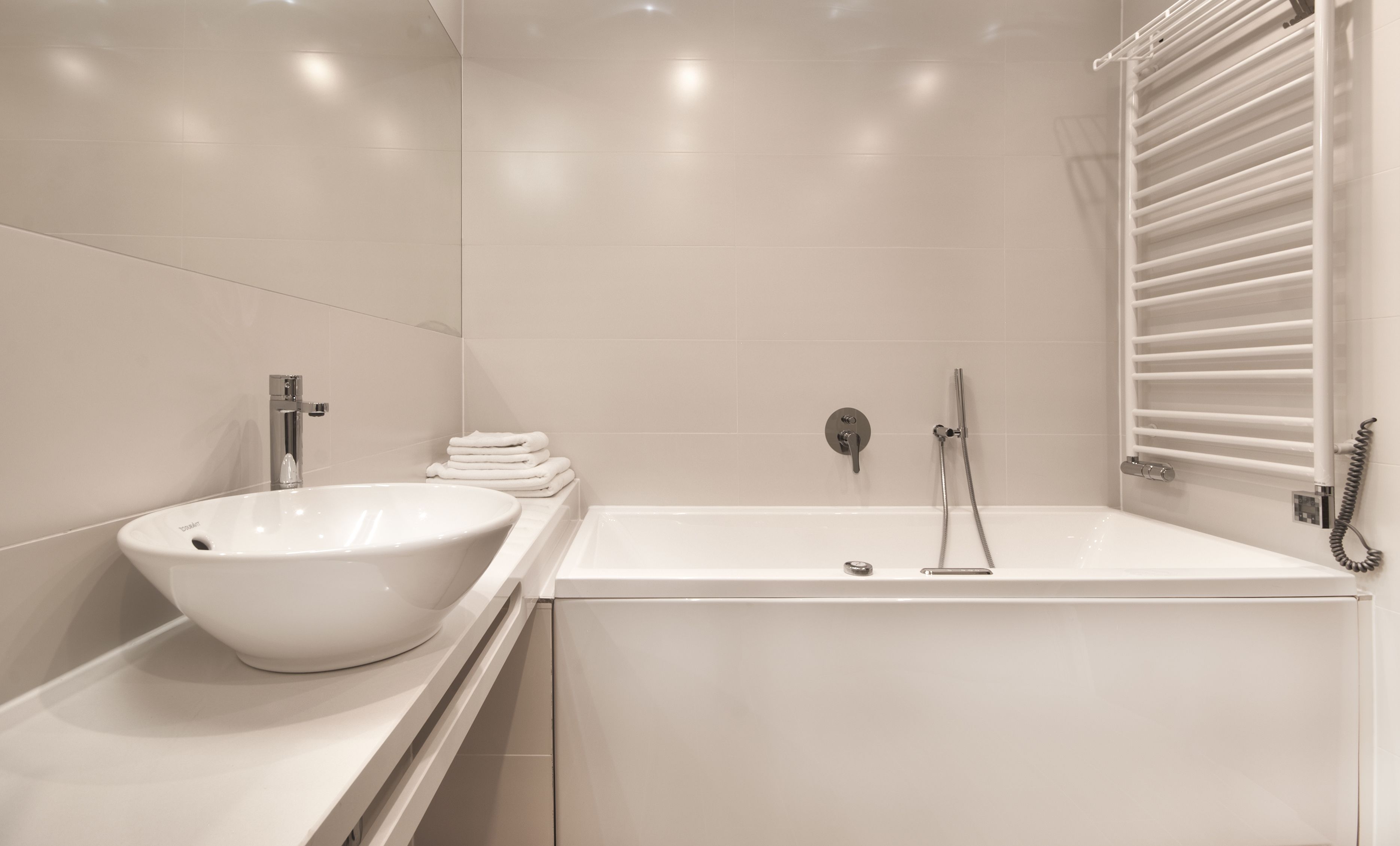 Een moderne badkamer met een witte wastafel, een bad en een douche.