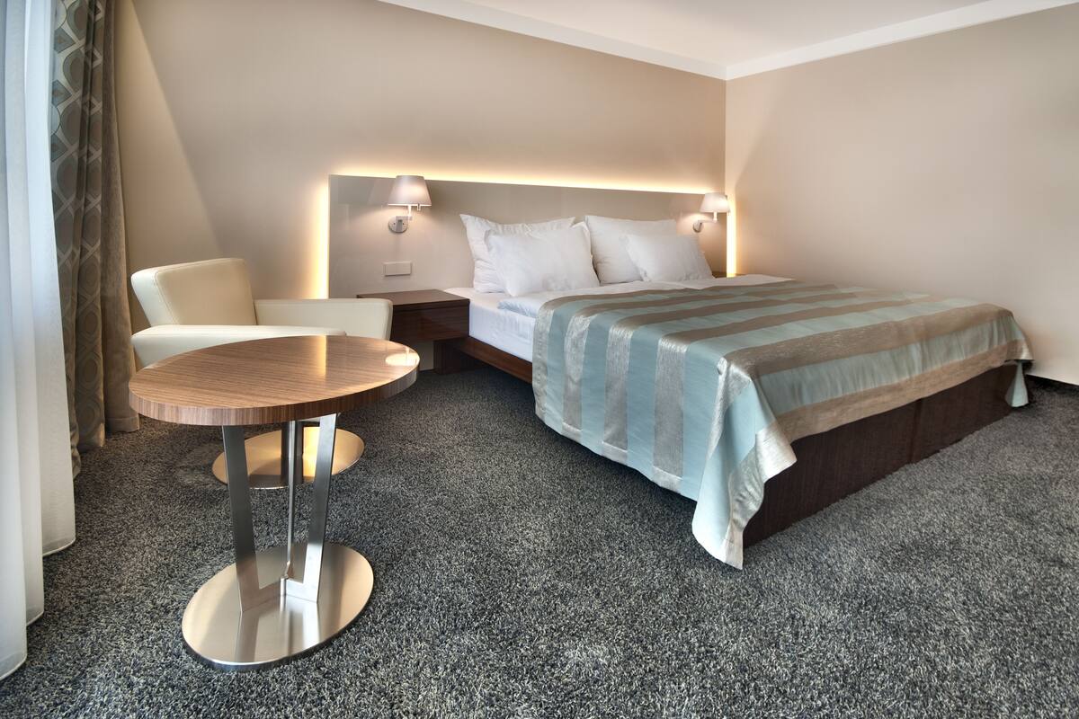 Une chambre d’hôtel avec un lit, une table ronde, une chaise et une table de chevet.