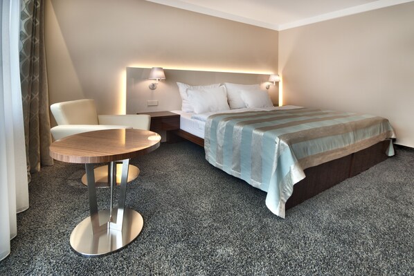 Une chambre d’hôtel avec un lit, une table ronde, une chaise et une table de chevet.