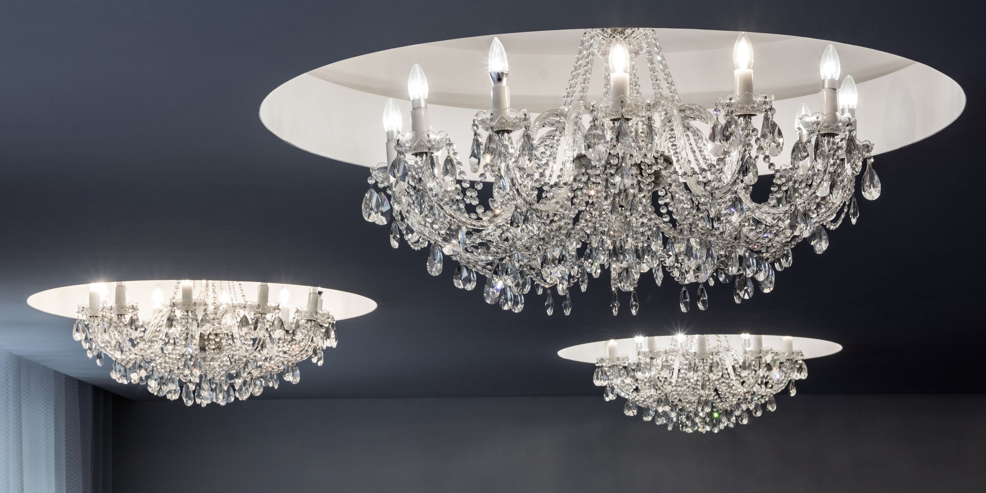 Three chandeliers with crystal decorations hanging from a ceiling.