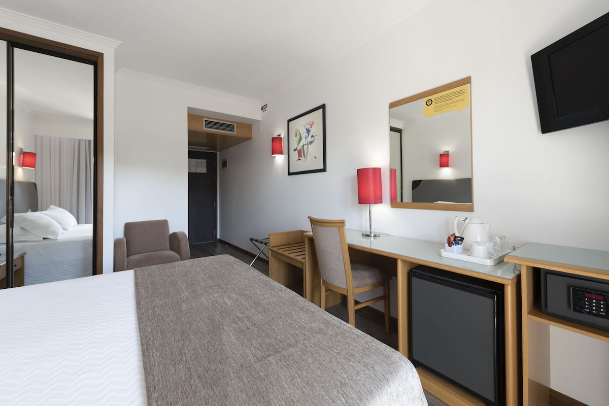 Ein Hotelzimmer mit Bett, Schreibtisch, Stuhl und einem kleinen Kühlschrank.