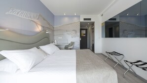 Une chambre d’hôtel moderne dotée d’un grand lit, d’un bureau et d’un coin salon avec des fauteuils.
