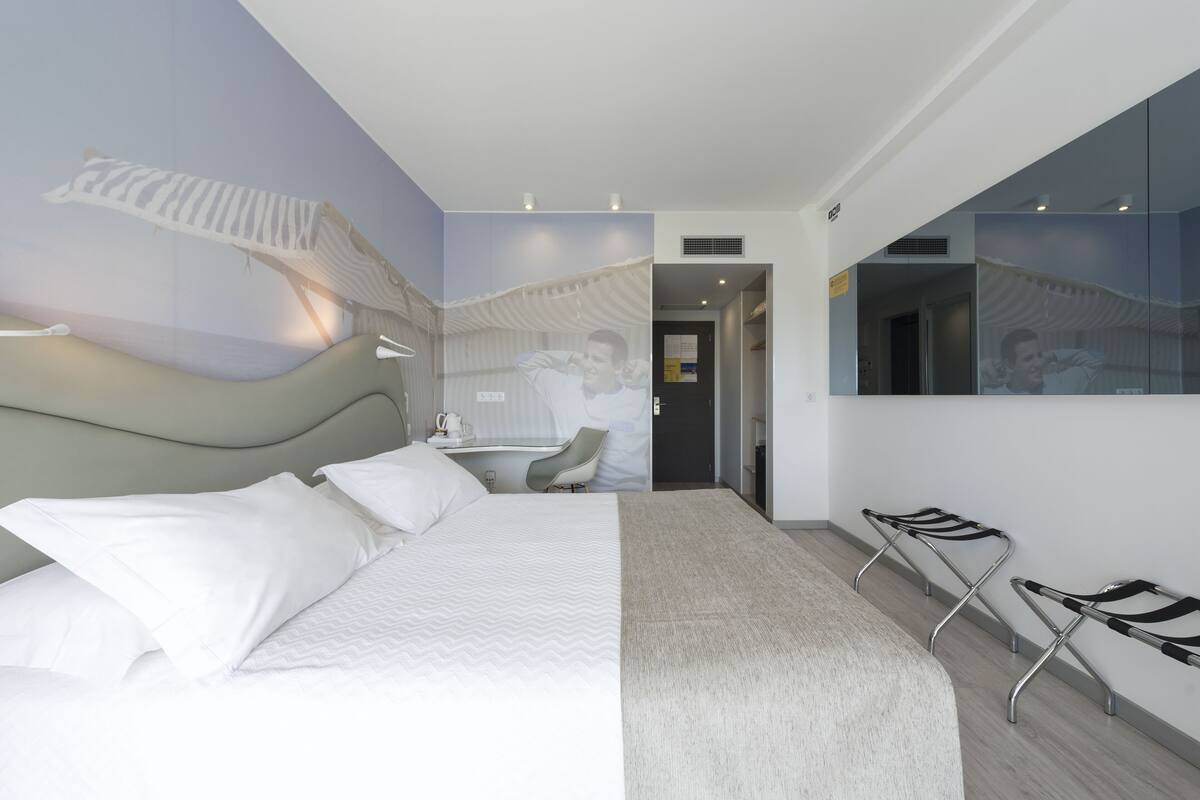 Ein modernes Hotelzimmer mit einem großen Bett, einem Schreibtisch und einer Sitzecke mit Stühlen.