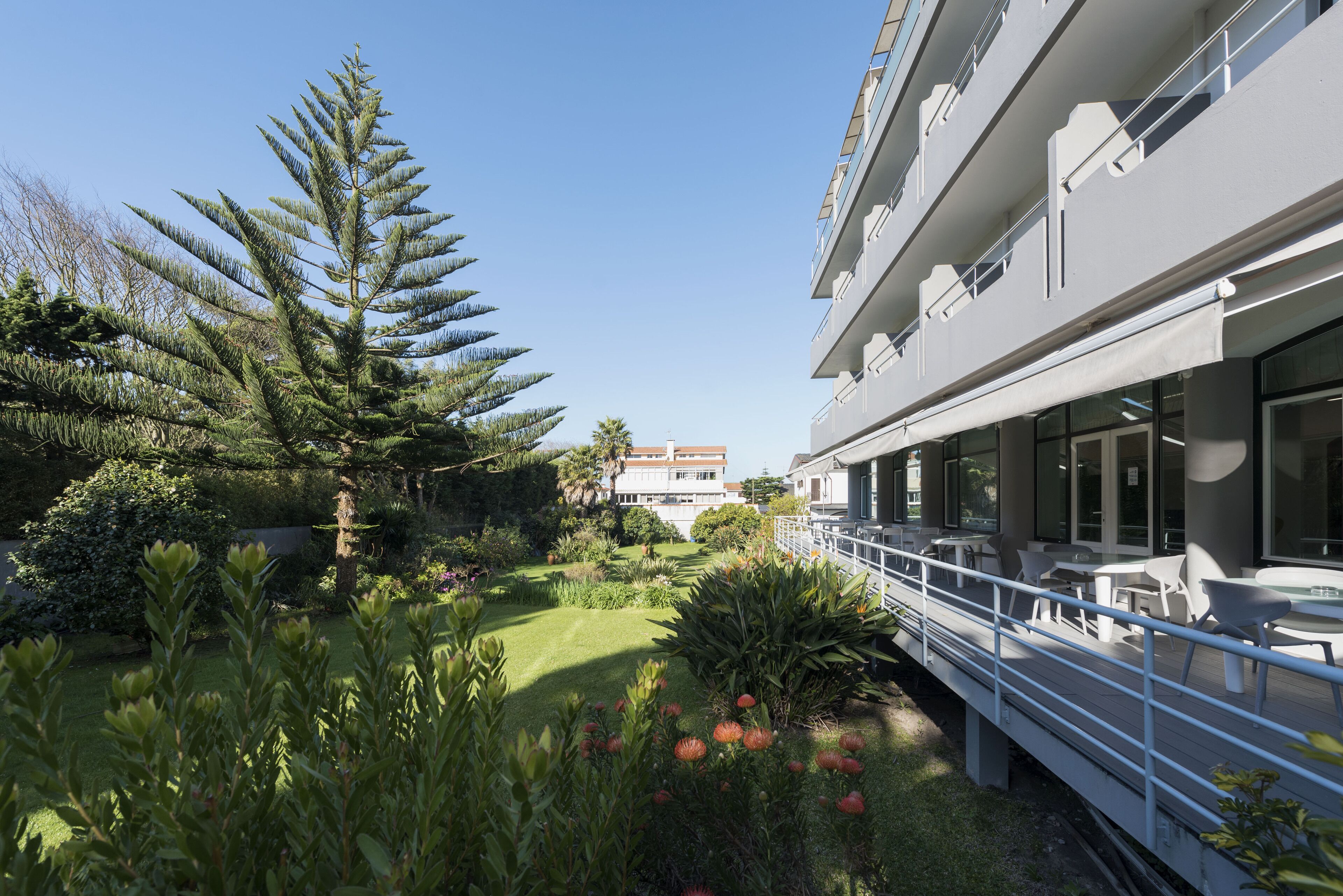 A modern hotel with a rooftop garden, outdoor seating, and a view of the cityscape.