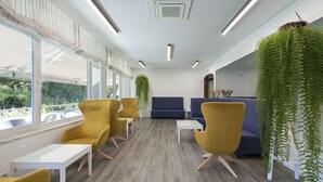 Un espace d’attente moderne avec des chaises jaunes, un canapé bleu et une table blanche.