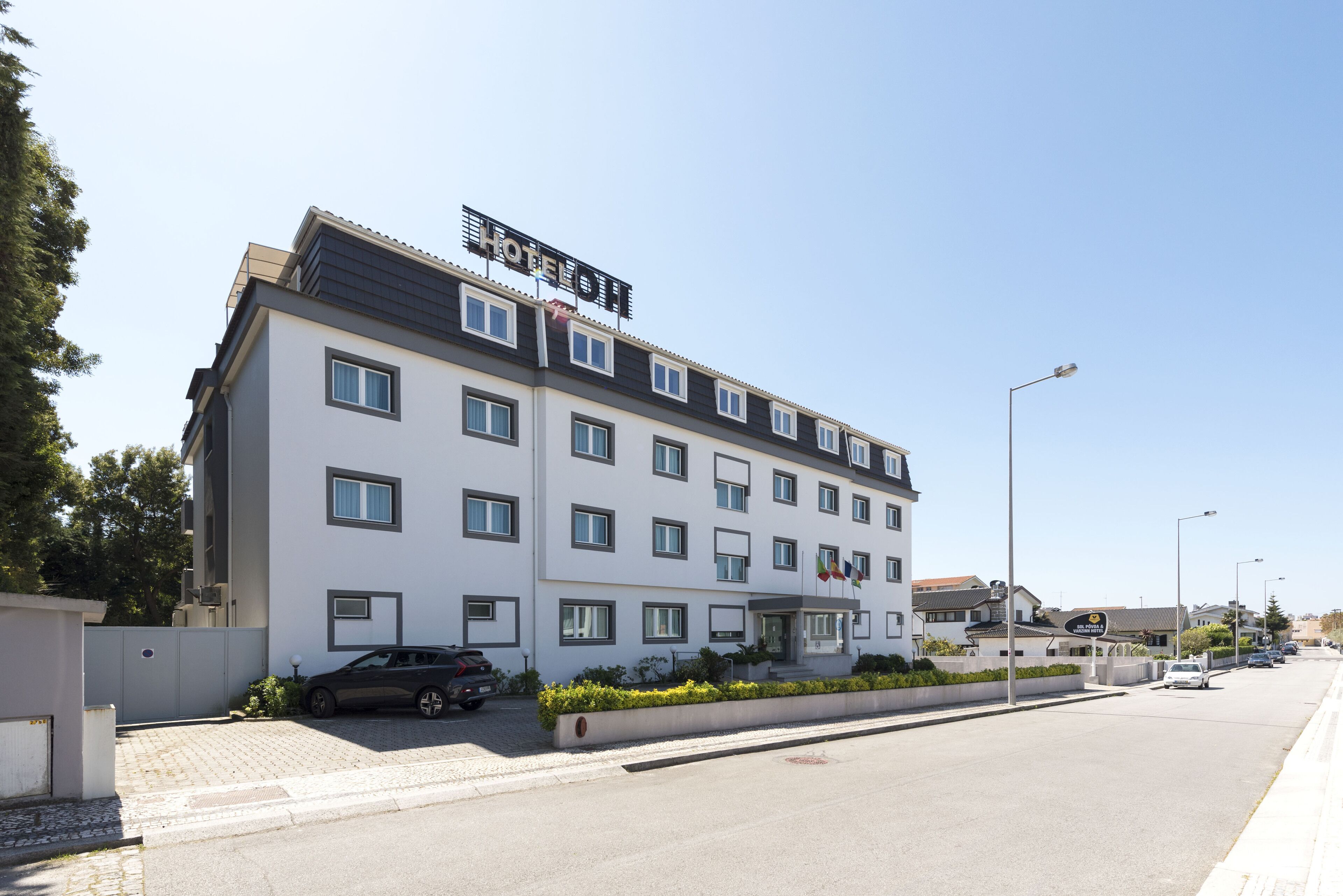 A modern hotel with a flat roof, multiple windows, and a sign indicating it is a hotel.