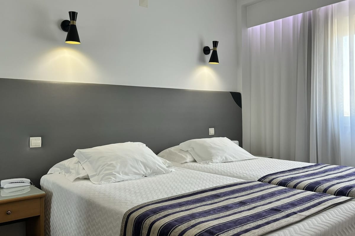 Ein Hotelzimmer mit zwei Betten, einem Nachttisch und zwei Wandlampen.