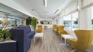 Un espace de bureau moderne avec un canapé bleu, des chaises jaunes et une table blanche.
