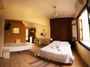 A hotel room with two single beds, a small kitchenette, a dining area, and a large window with a view. - Iason Studios (Chania)
