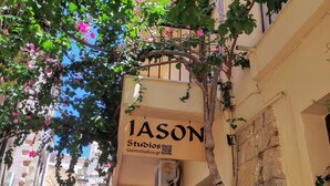 A narrow street with a building labeled "IASON Studios" and a tree with pink flowers. - Iason Studios (Chania)