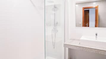 A modern bathroom with a glass-enclosed shower, a white sink, and a mirror with a wooden frame.