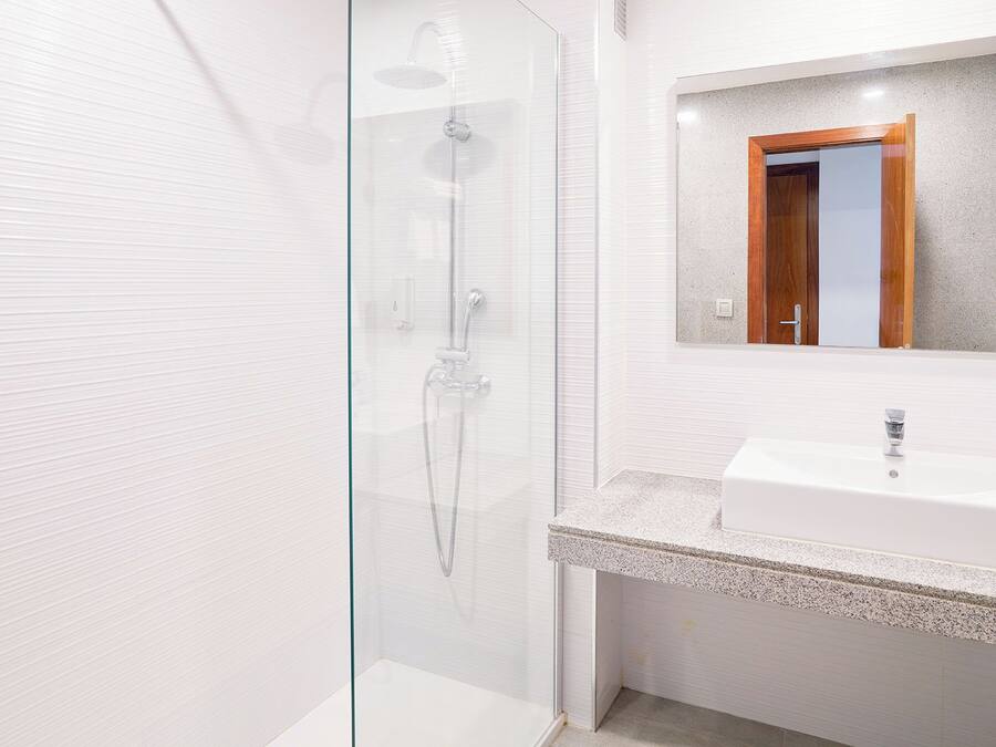 A modern bathroom with a glass-enclosed shower, a white sink, and a mirror with a wooden frame.