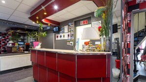 A reception area with a red counter, a white lamp, and a fire extinguisher. - Hôtel de l'Europe (Paris)