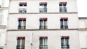 A building with multiple windows, each with a red awning and the letters "H.E" on them. - Hôtel de l'Europe (Paris)